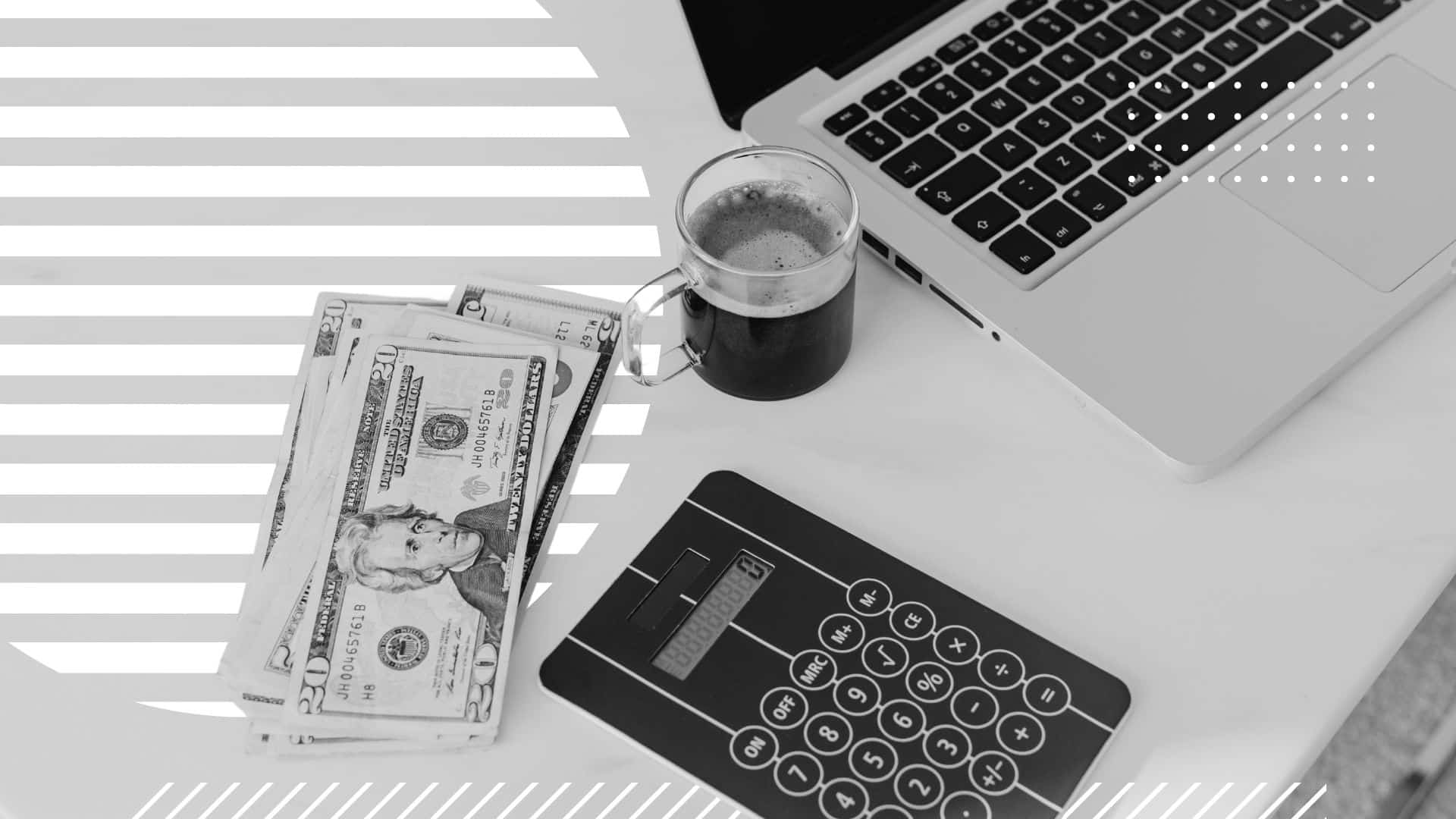 Close up of a corner of a desk, on which a stack of US currency sits beside a calculator, a cup of coffee, and the corner of a laptop