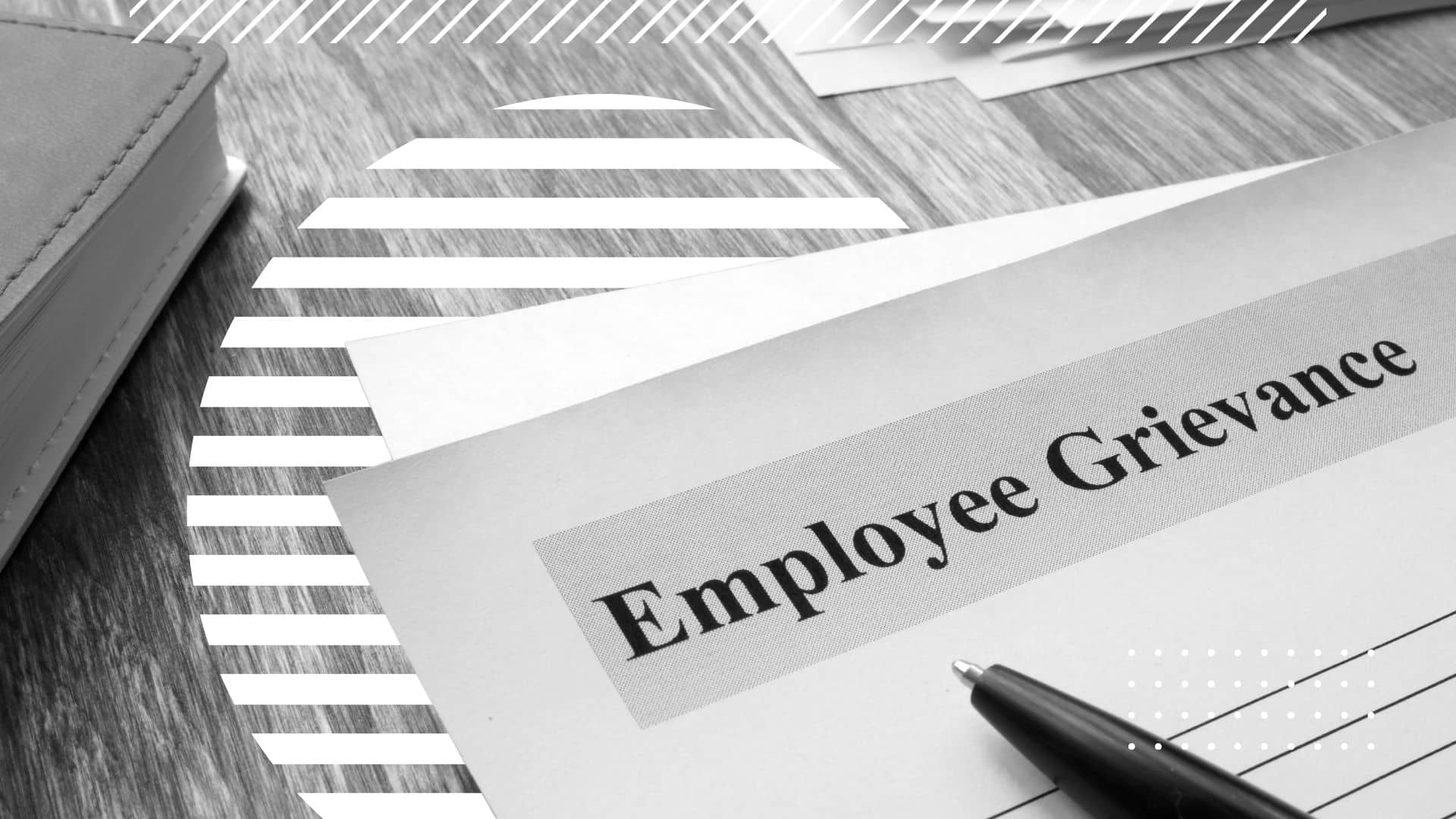 Employee Grievance form on a desk, a pen rests on the paper and beside it is the corner of a notebook just out of frame