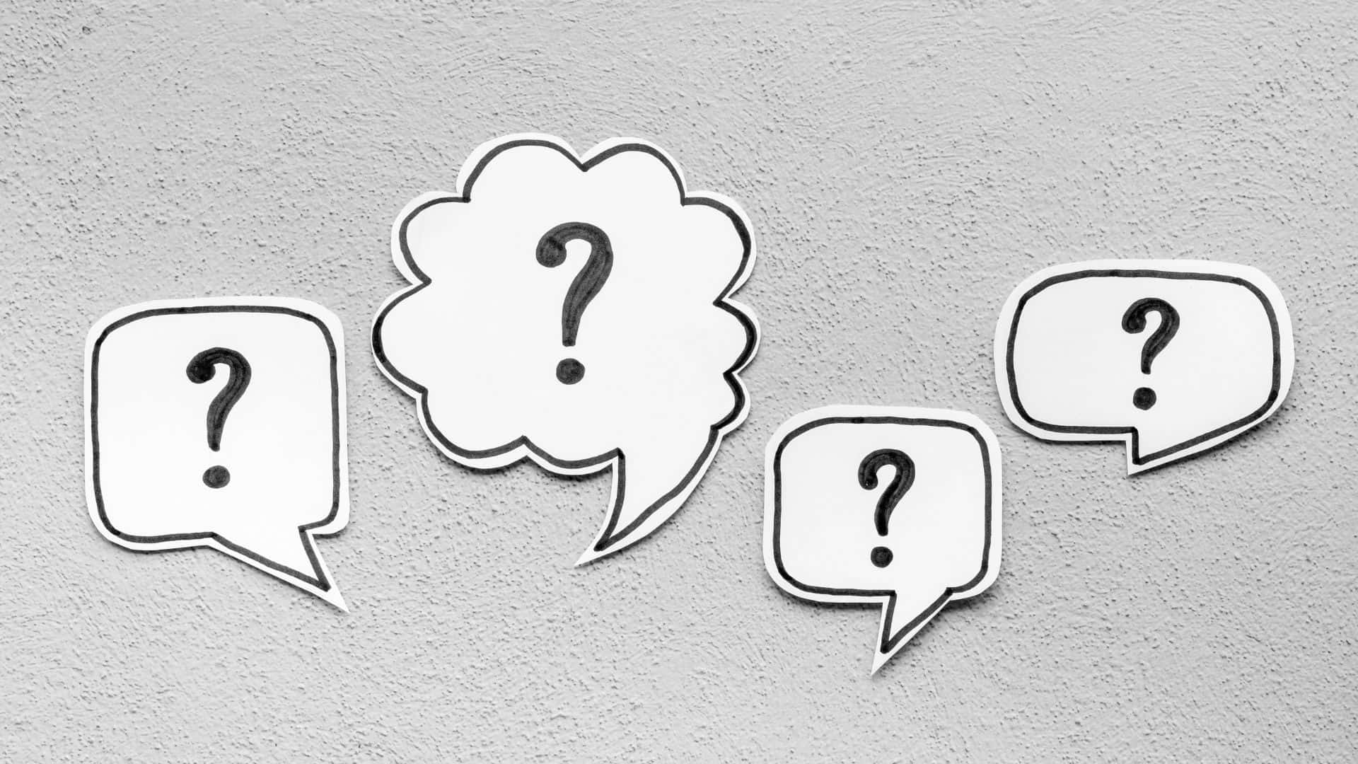 Paper cutouts of speech bubbles with a single question mark printed on each of the four
