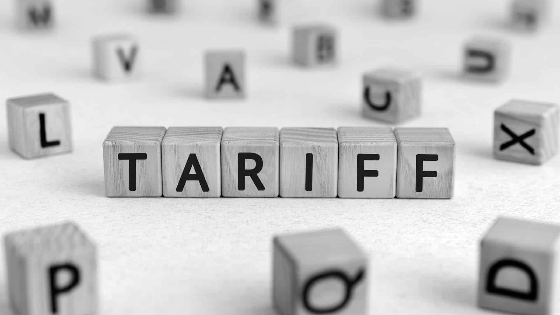 small wooden blocks with letters on them, in the center they spell out "tariff"